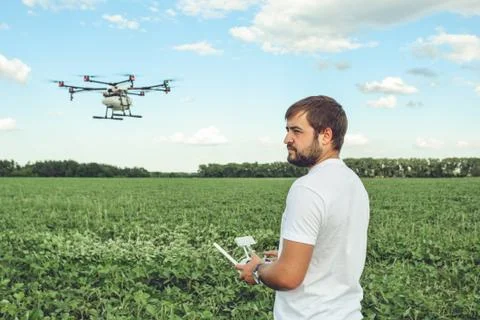 Young man operating of flying drone octocopter at the green field. Stock Photos