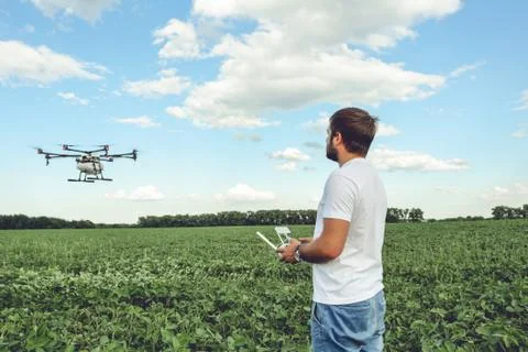 Young man operating of flying drone octocopter at the green field. Stock Photos