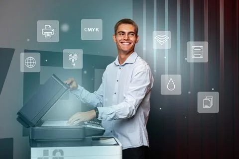 Young man operating a modern printer in a bright office setting during daytime Stock Photos