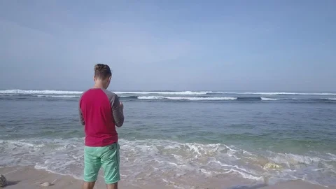 Young man operating quadcopter drone using remote control on seashore. Stock Footage 84629038