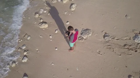 Young man operating quadcopter drone using remote control on seashore. Stock Footage 84629171