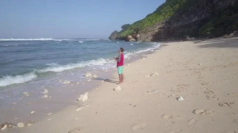 Young man operating quadcopter drone using remote control on seashore. Stock Footage 84629232