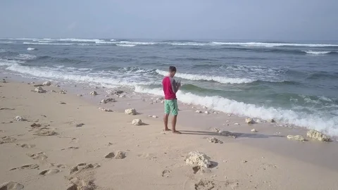 Young man operating quadcopter drone using remote control on seashore. Stock Footage 84629466