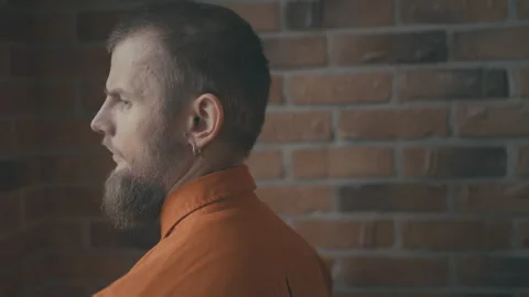 Young man in orange robe in prison for breaking the law, punishment for crime Stock Footage 245303396