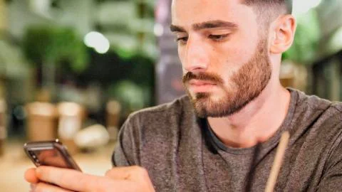 Young man outside at night using phone Stock Photos