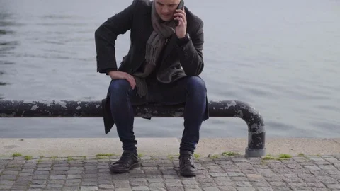 Young man in overcoat using a mobile outdoors Stock Footage 117349530