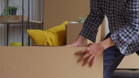 Young man packing cardboard boxes for house relocation in new apartment. Stock Footage 337756084