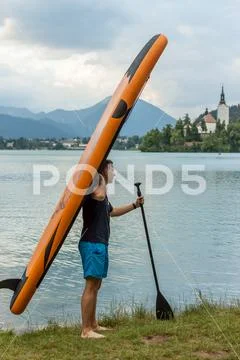 Young man with paddle board on the lake Stock Photos