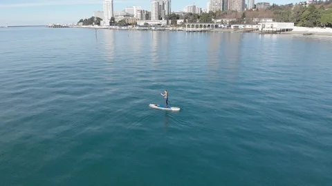 The young man is paddling on SUP surf in the sea near a city Stock Footage 99252947
