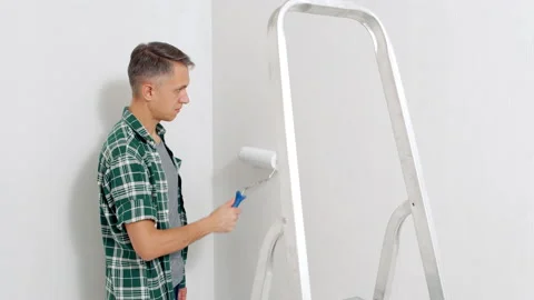Young man painting the wall with a roller. Renovation and new housing concept Stock Footage 143550007