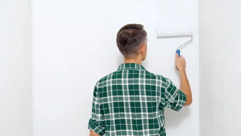 Young man painting the wall using a roller. View from the back. Copy space Stock Footage 144502147