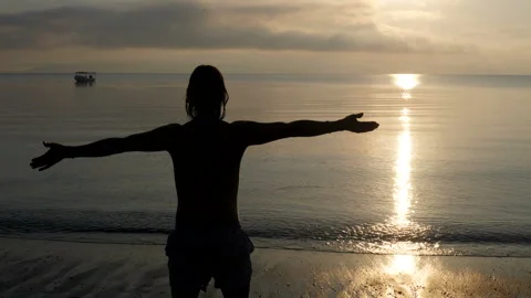 Young man on a paradise beach at dawn Stock Footage 130665992