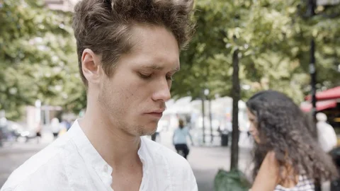 Young man in a park scrolling through his phone with his girlfriend in the Stock Footage 115919405