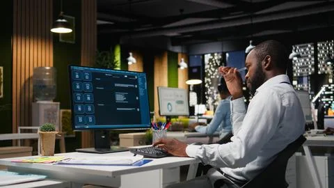 Young man PC user interacting with AI chat system on pc at office late at night Stock Photos