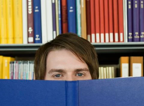 Young Man Peeking Over Opened Book Stock Photos