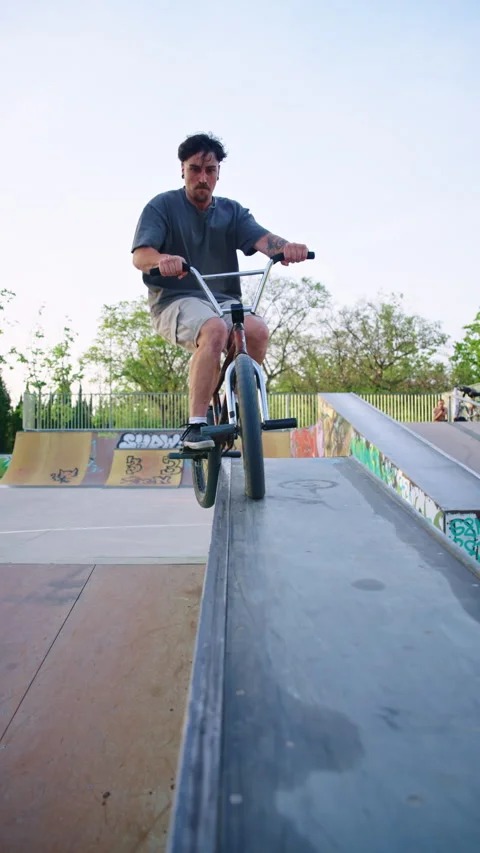 Young man performing BMX grind trick on rail in skatepark, slow motion urban Stock Footage 336937041