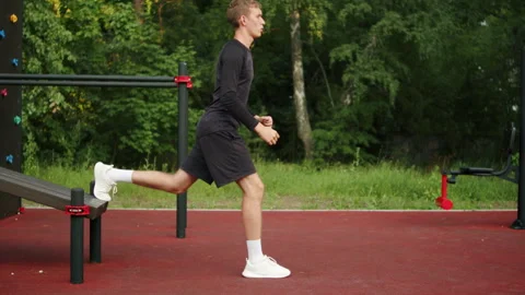 Young man performing a Bulgarian split squat with his back foot elevated on.. Stock Footage 341730396