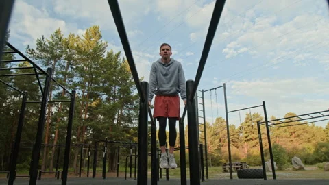Young Man Performing L-Sit on Parallel Dip Bars in Outdoor Gym Video stock 315181582