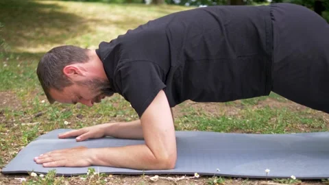 Young man performing plank exercise in public park during workout Stock Footage 335696579