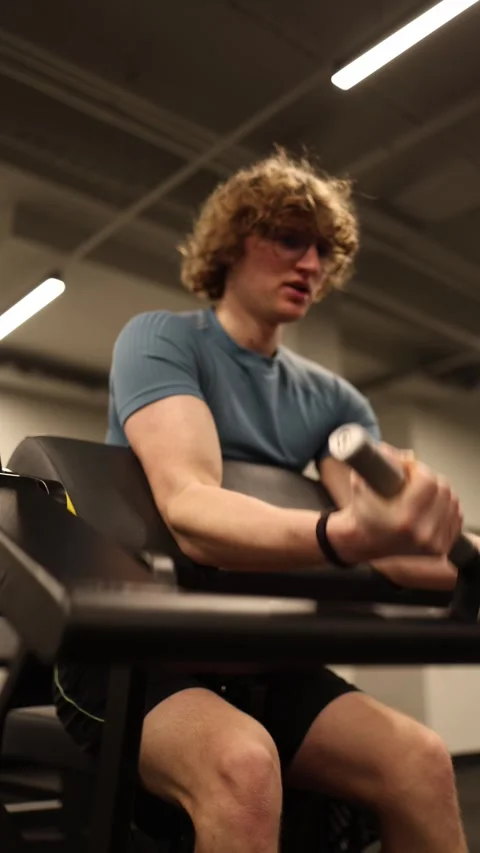 The young man is performing a preacher curl exercise to target his biceps, demon Stock Footage 301676902