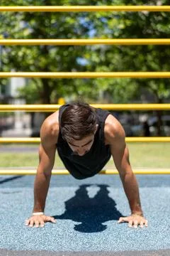 Young man performing a push-up at an outdoor fitness park Stock Photos