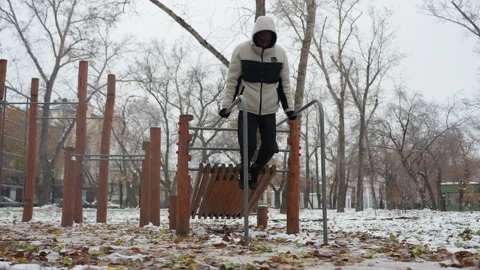 Young Man Performing Strength Training on Parallel Bars in Snowy Urban Park Stock-Footage 305628813