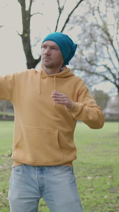 Young man performing tai chi exercises in a public park Stock Footage 327233986