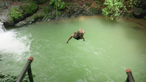Young Man Performs Backflip Dive Into Tropical Waterfall Pool in Slow Motion. Stock Footage 338366559