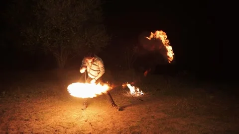 A young man performs a fire show. Swings a flame ball. Video stock 289832616