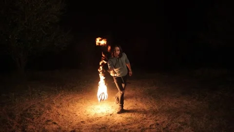 A young man performs a fire show at night. Swings a flame ball. Video stock 291253441