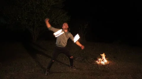 A young man performs a fire show. Swings a flame ball. Video stock 291253907