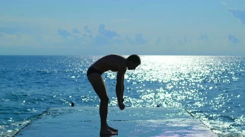 A young man performs physical exercises on the background of the sea. Stock Footage 142762169