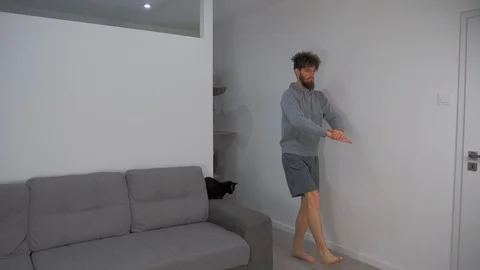 Young Man Performs Pistol Squat, Home Workout in Living Room, Static Shot Stock Footage 127986360