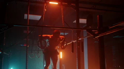 Young man performs pull-ups on gymnastic rings crossfit training day training Stock Footage 170612540