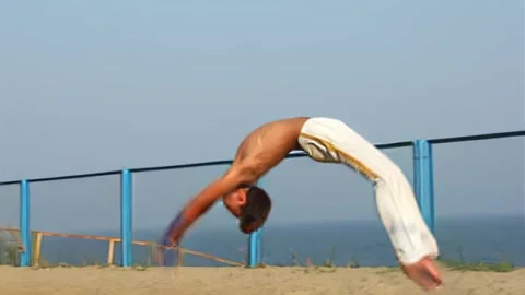 A young man performs several acrobatic flips in a row and crashes into a fence. Stock Footage 337427435