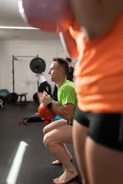 A young man performs squats holding the kettlebell Foto stock