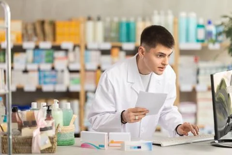 Young man pharmacist uses computer at workplace Foto stock
