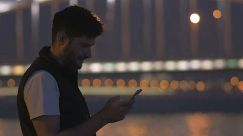 Young man with phone looking at the bridge of Perth, the great, Neva river Stock Footage 64908703