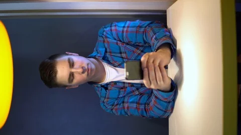 A young man with a phone sits at a table. A man sits at cafe at a table with a Stock Footage 126504424