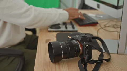 Young man photographer with mirrorless camera and lens on desk, hand typing.. Stock Footage 337377192