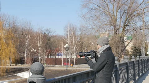 Young man Photographer With professional Camera Equipped in Black Parka Taking Stockbeeldmateriaal 67352576
