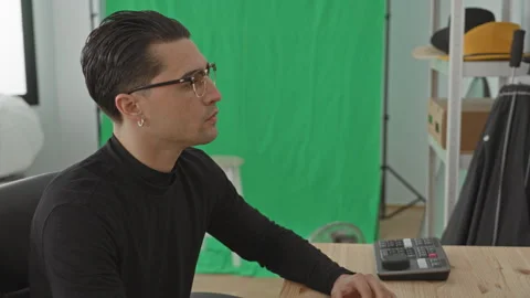 Young man photographer at studio desk operating a console with hand on cont.. Stock Footage 337436230