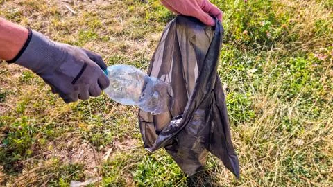 Young man picking up plastic bottle with gloved hand Stock Photos