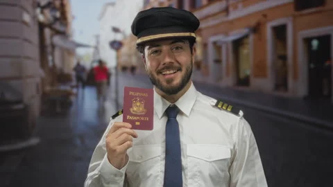 Young man in pilot uniform holds a philippine passport, smiling outdoors on.. Stock Footage 308593587