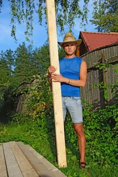 A young man with the pine Board in the hands of about a pile of Stock Photos
