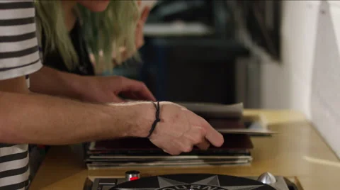 Young man placing vinyl record on turntable in music store Vídeo Stock 58582166