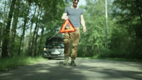 Young Man Placing the Warning Triangle in Front of his Car Stock Footage 79734957