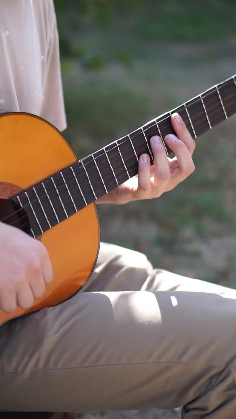 Young man is playing acoustic guitar outside Stock Footage 283576534
