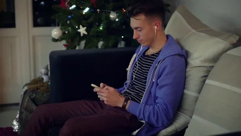 A young man playing around with his cell phone while listening the music with Vidéo 78493209