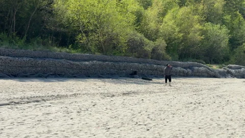 A young man is playing with a ball on a white sandy beach. The sun is shining, t Stock Footage 310826473